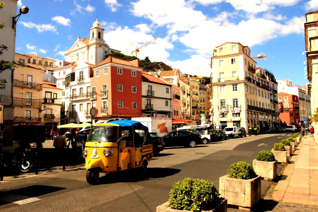 Alfama with yellow tuktuk and red house