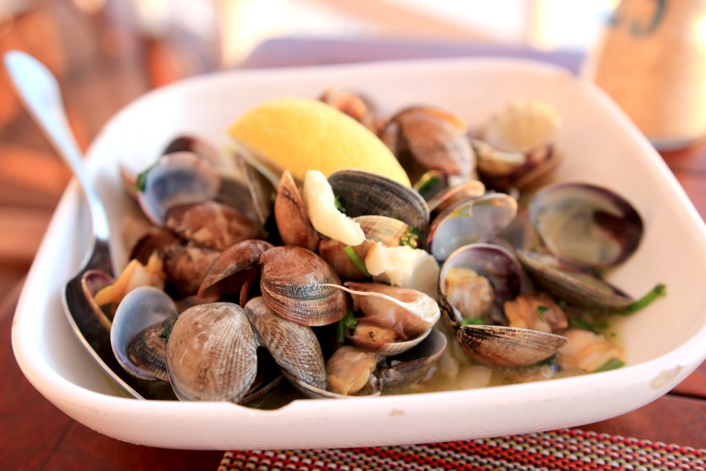 Clams shells in white plate with lemon quarter